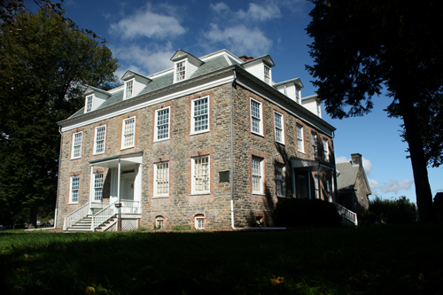 Van Cortlandt House Museum stands tall as shadows cast over it in the evening. 